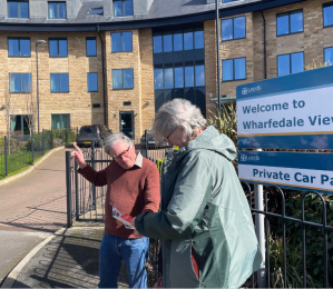 two people discussing a Labour party leaflet outside Wharfedale View care apartments - Leeds City Council sign welcome to Wharfedale View
